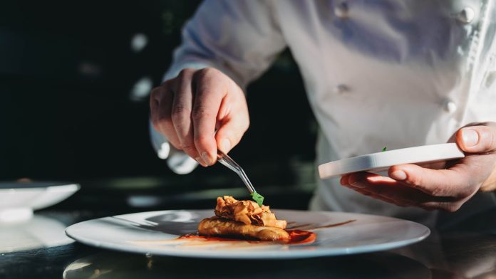 A chef is finishing the preparation of the plate